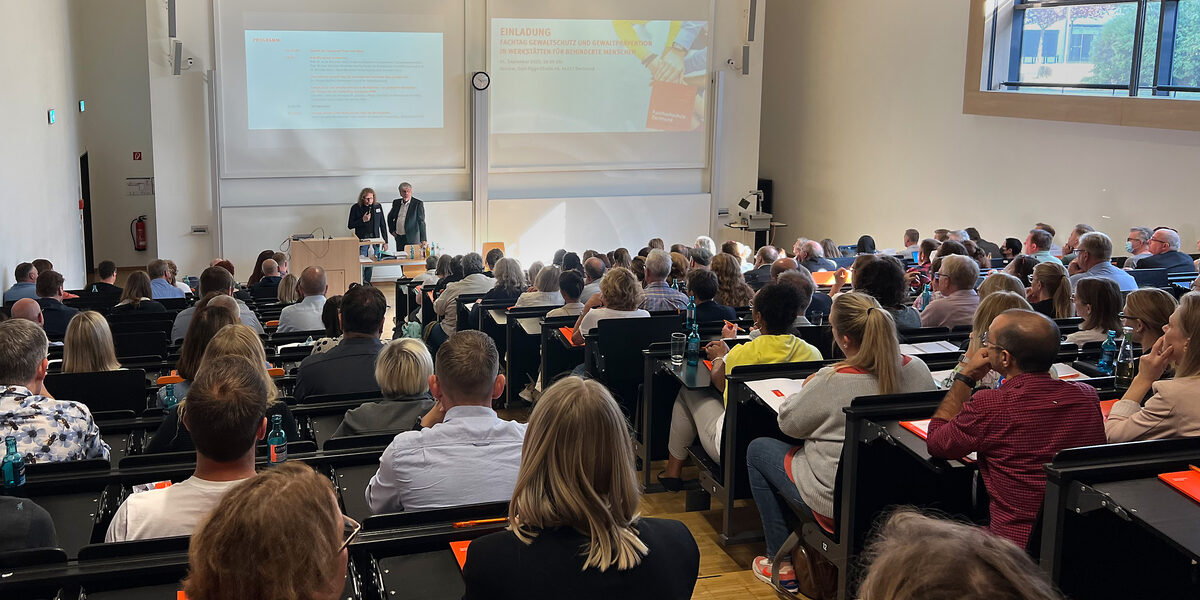 Menschen sitzen in einem Hörsaal und verfolgen einen Vortrag.