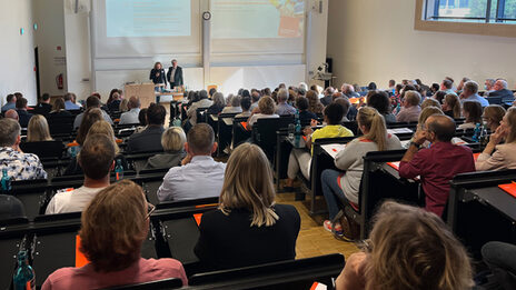 Menschen sitzen in einem Hörsaal und verfolgen einen Vortrag.