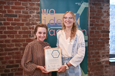 Two people holding a framed certificate.