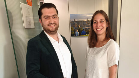 Zwei Personen stehen nebeneinander vor einer geöffneten Tür.