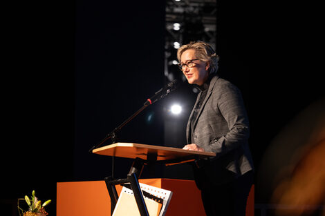 A person speaks at a lectern and looks to the left out of the picture.