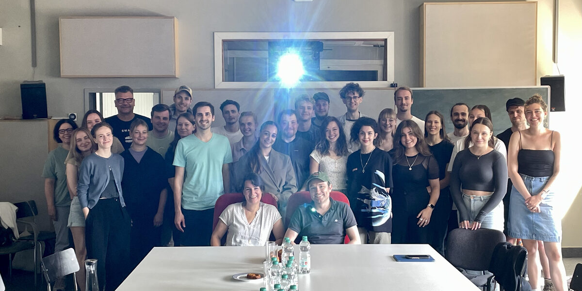 The light from a film projector shines above a group of people in the seminar room.