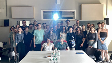 The light from a film projector shines above a group of people in the seminar room.