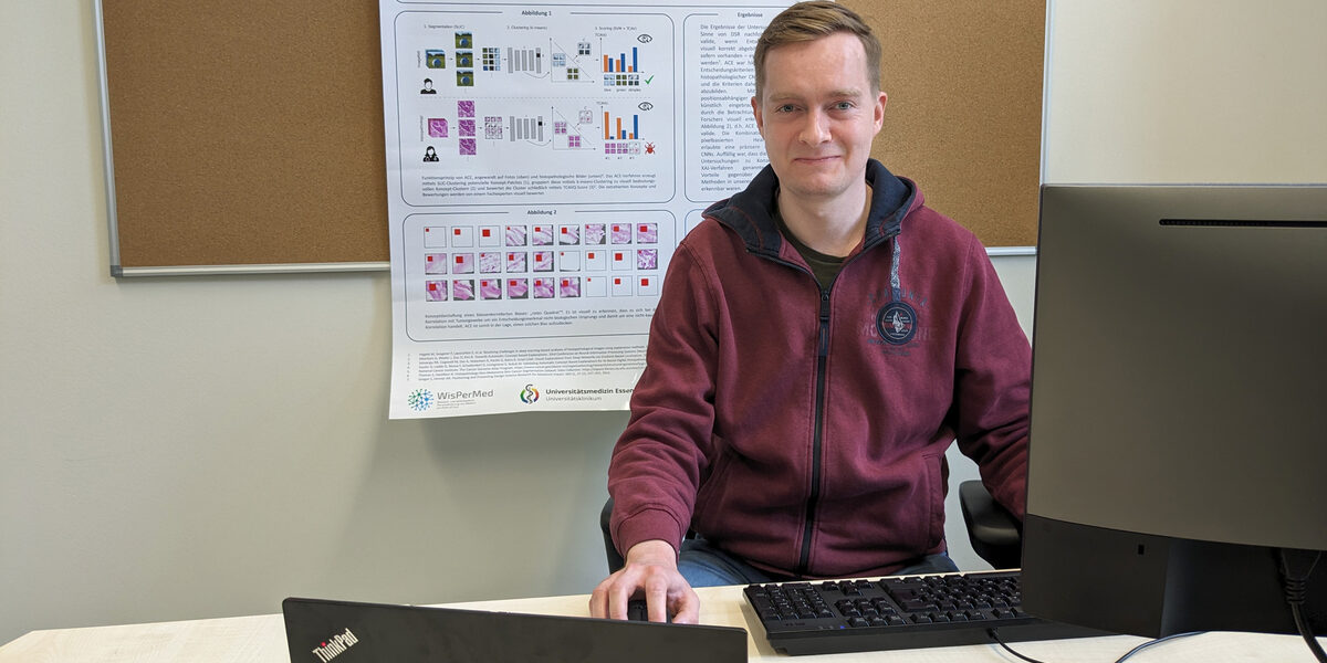 A male person is sitting at a desk and working on a computer.