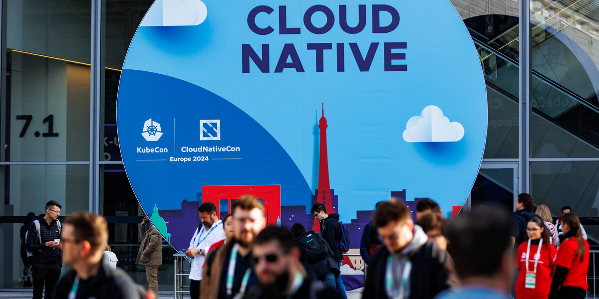 People walk to the entrance of the fair. The trade fair logo is shown in the background.