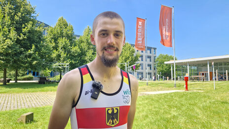 Eine Person ist bekleidet mit einem Deutschlandtrikot und steht auf einem begrünten Gelände.