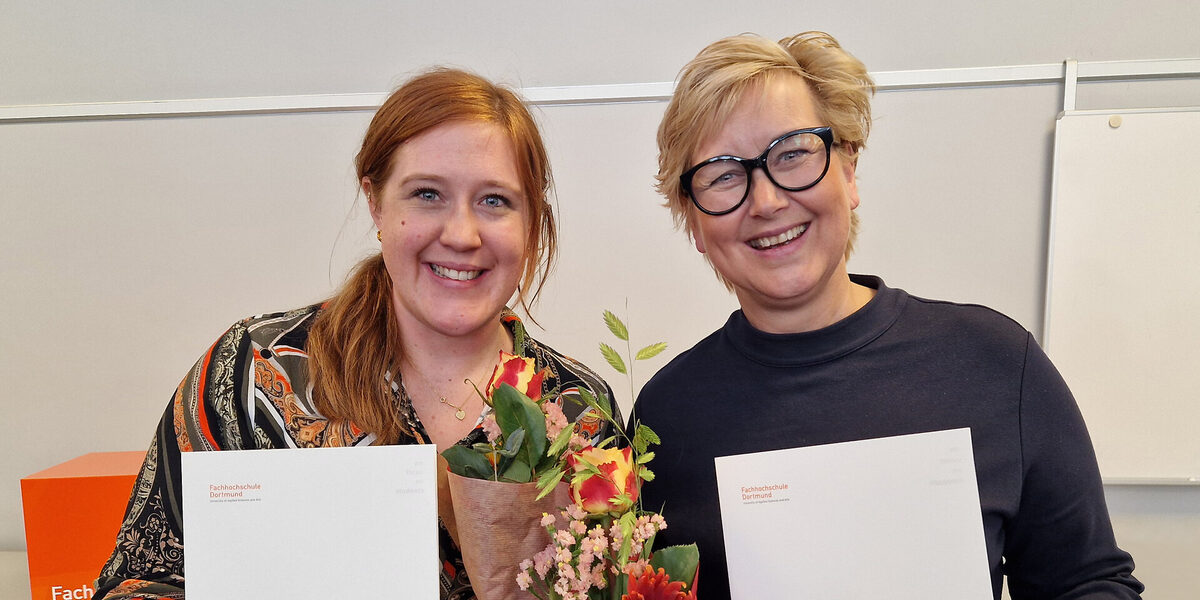 Two people are standing next to each other, each holding a bouquet of flowers and a white folder in front of them.