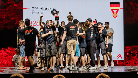 People cheer and hold up trophies.