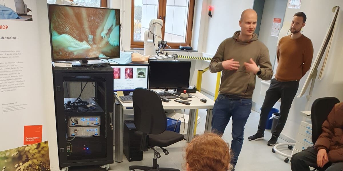 A group of pupils listens to a presentation by a member of staff in the laboratory.