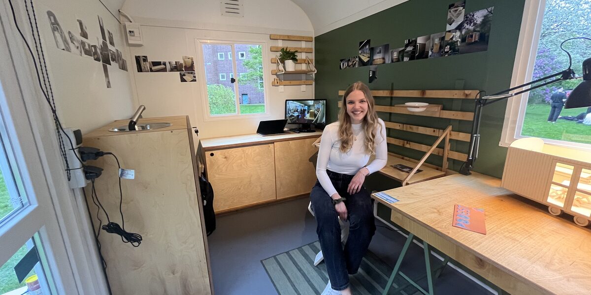 A female figure sits in a converted construction trailer.