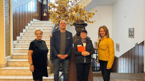 Vier Personen stehen in einem repräsentativen Treppenhaus.