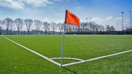 Auf einem Fußballfeld steht eine Eckfahne im Vordergrund.