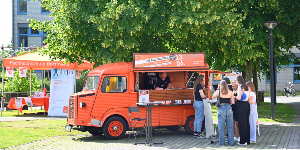 People stand in front of the orange-colored HY of Fachhochschule Dortmund.