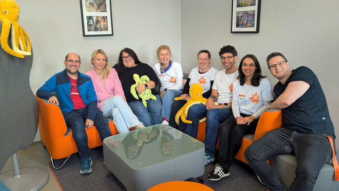 A group of people are sitting close together in the corner of a sofa.