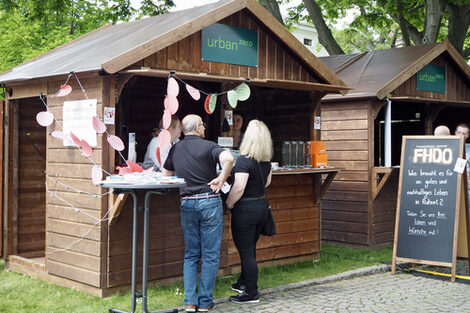 Zwei Personen informieren sich an einem Infostand. Der Aufsteller zeigt, dass der Stand zur FH Dortmund gehört.