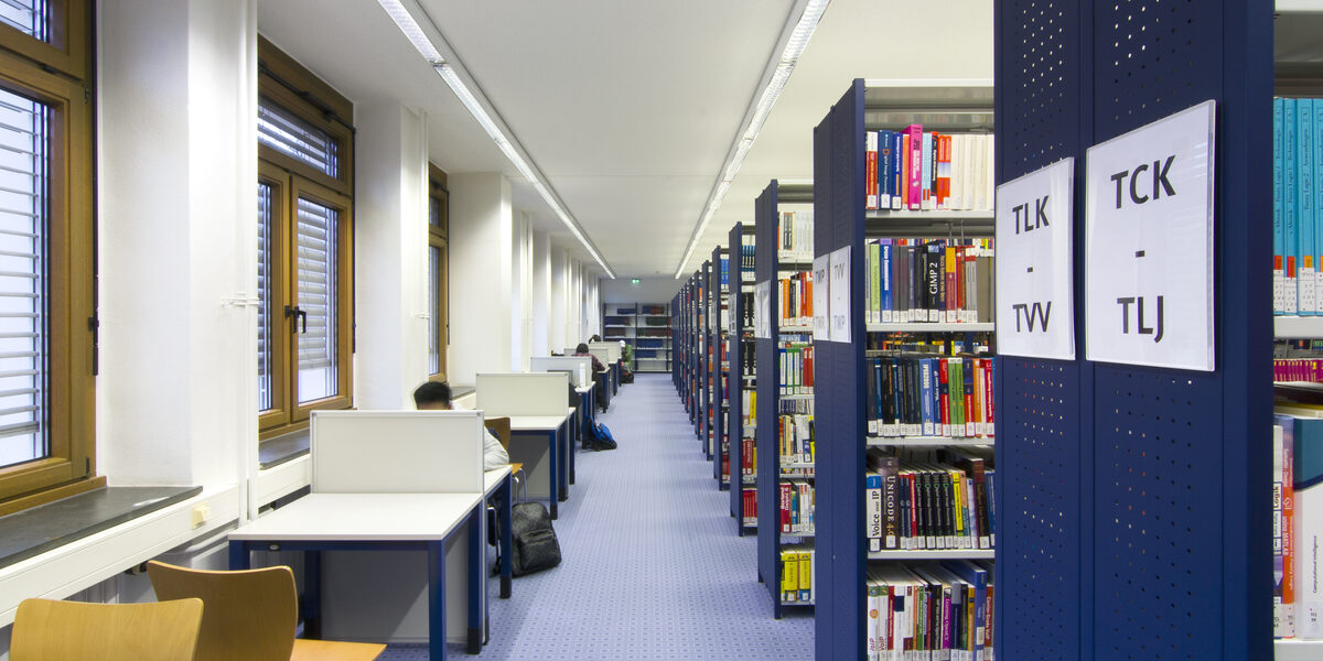 Foto von Bücherregalreihen und Einzelarbeitsplätzen in der Bibliothek__Photo of library book shelves and desks