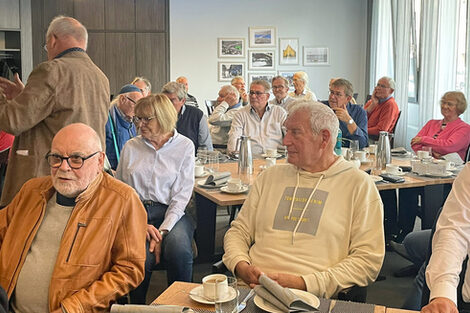 Menschen treffen sich in einem Raum und sprechen miteinander.