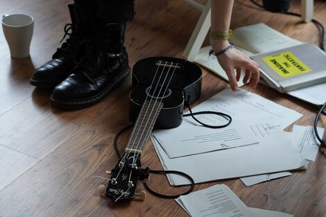 Eine Ukulele liegt neben verschiedenen Songtexten auf dem Boden