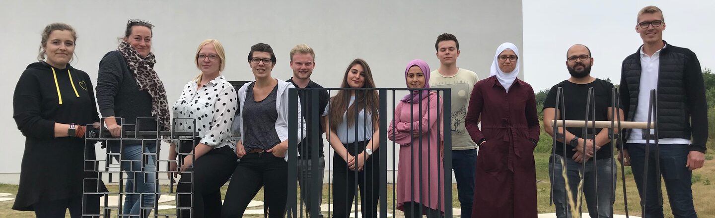 Group photo of the participating students on campus with three railing prototypes.