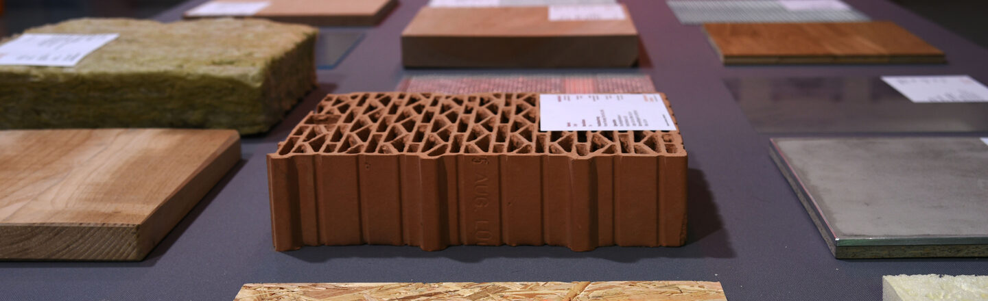 Square samples of different materials made of wood or stone lie on a table. They are provided with small explanatory labels.