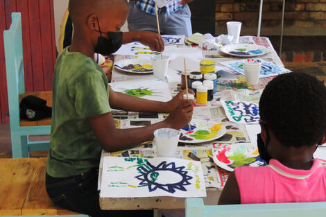 Children sit at a table and draw pictures.