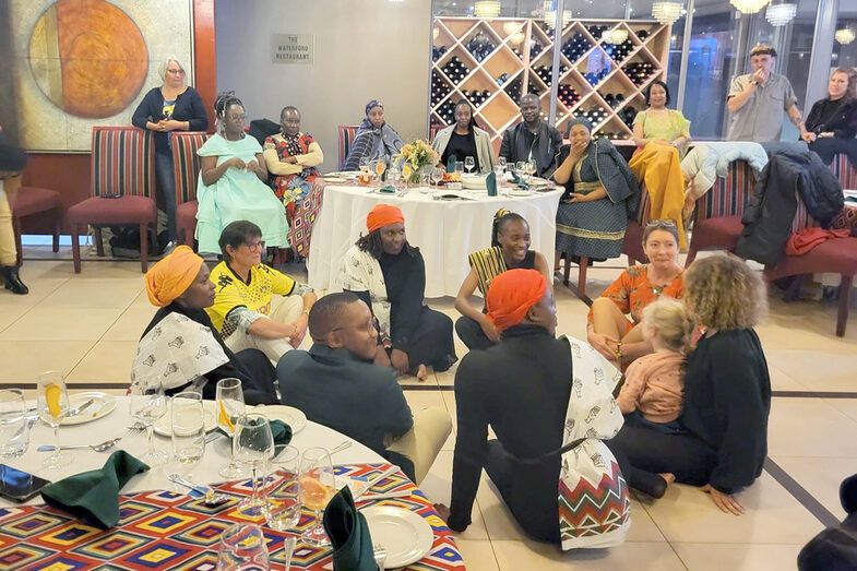 Several people are sitting in a circle and talking, with others standing in the background.