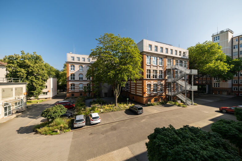 Gebäudeaufnahmen an der Sonnenstraße, im Vordergrund sieht man den Innenhof, mit mehreren Bäumen und ein paar Parkplätzen.