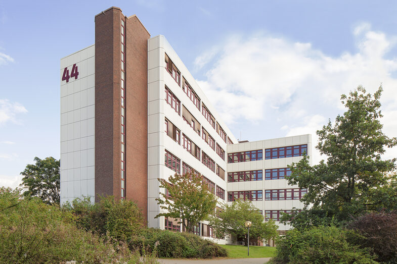 Photo of the building Emil-Figge-Straße 44 of the Fachhochschule Dortmund, in front of it bushes and trees.