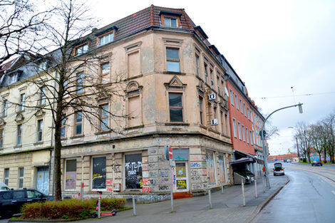 A vacant corner house with broken windows and graffiti